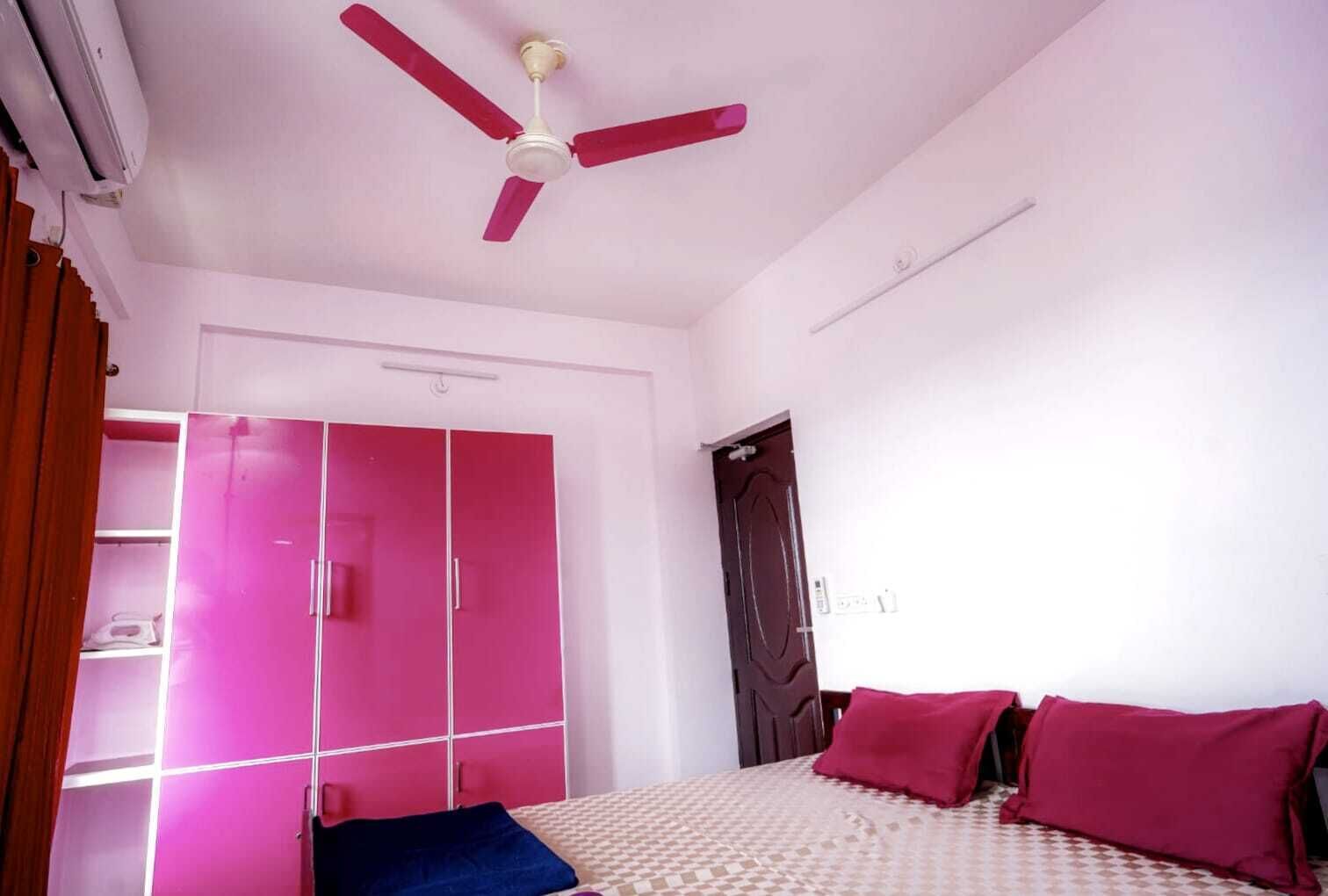 Ein Schlafzimmer mit Bett, Deckenventilator, Kleiderschrank und Tür.