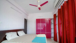 Quarto com cama, ventilador de teto, guarda-roupa e cortinas vermelhas.