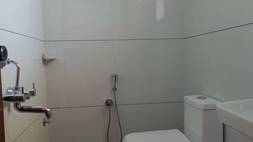 A small, modern bathroom with a toilet, a shower, and a hand dryer.