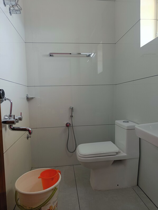 Une petite salle de bain moderne équipée de toilettes, d’une douche et d’un sèche-mains.