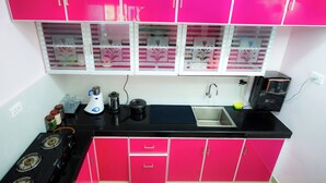 Uma cozinha com armários rosa, bancada preta, fogão e pia.