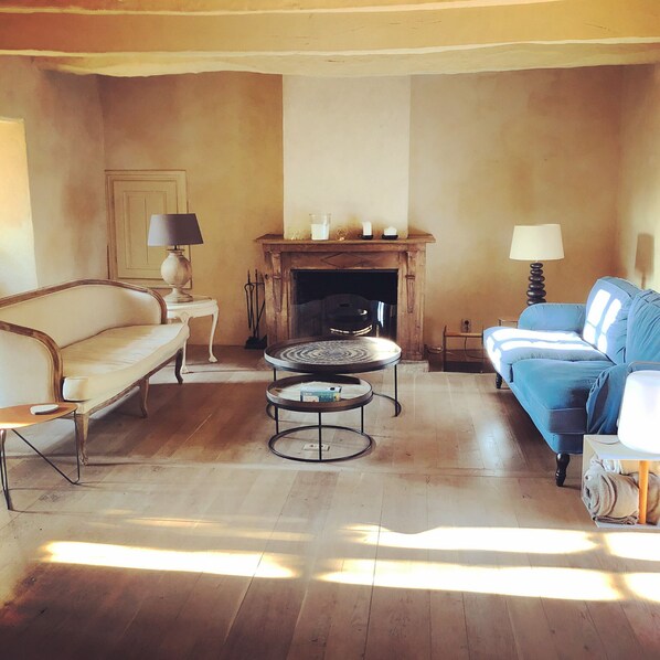 Una sala de estar con sofá, un diván azul, una mesa de centro y una chimenea.