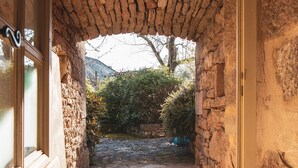 Un corridoio con pareti in pietra e pavimento piastrellato che conduce a una zona esterna.