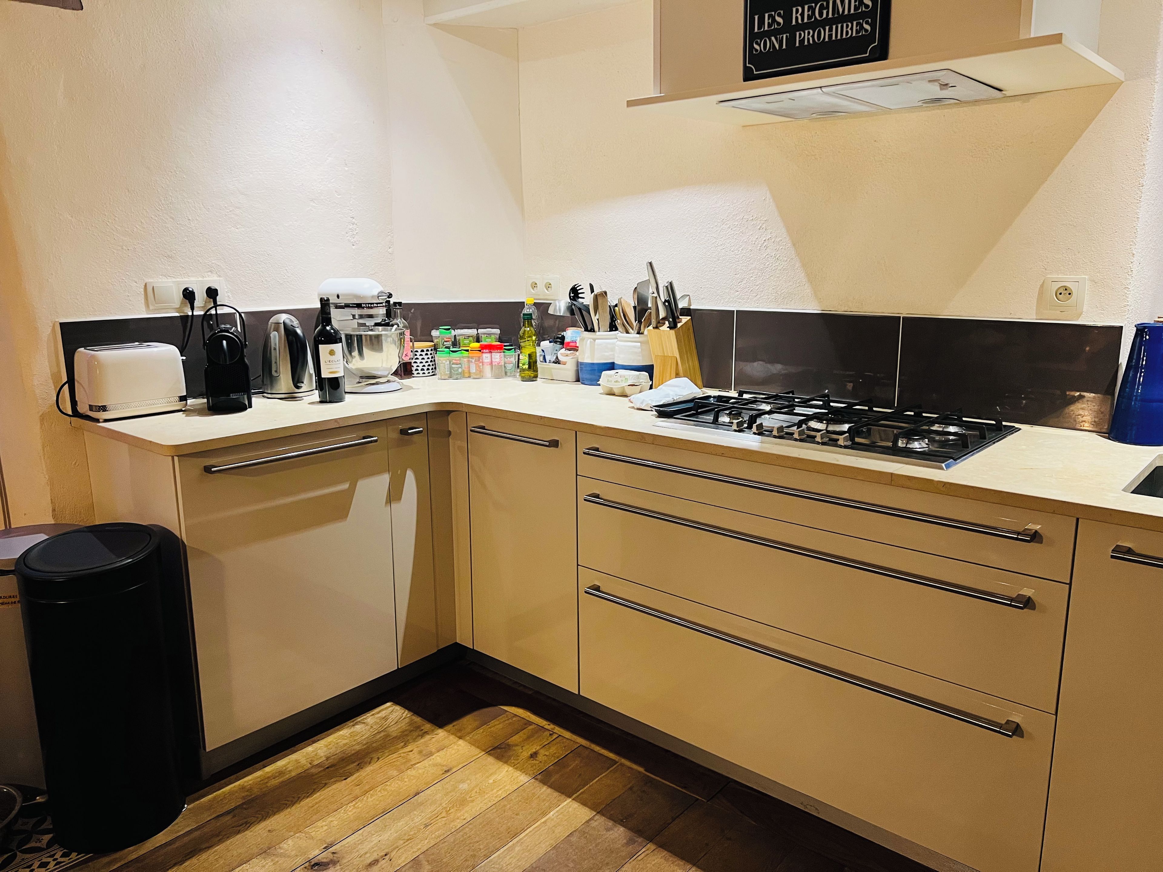 Een kleine keuken met een gasfornuis, een koffiezetapparaat en diverse keukengerei.
