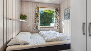 A small, cozy bedroom with a single bed, a window with patterned curtains, a shelf with a plant, and a framed picture on the wall. - "Viljo" - 30km from the sea by Interhome (Toftlund)