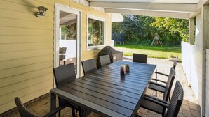 A covered patio with a table and chairs, a sliding glass door, and a view of a backyard. - "Viljo" - 30km from the sea by Interhome (Toftlund)