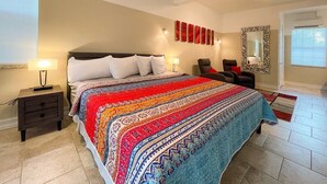Un dormitorio con una cama grande, una mesita de noche, una silla, un espejo y una ventana.