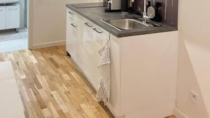 Una cucina moderna con mobili bianchi, un forno a microonde, un lavello e una macchina per il caffè.