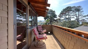 Une terrasse couverte avec des poutres en bois et un mur en briques, agrémentée de deux chaises à rayures et d’une table.