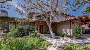 Une maison avec un chemin de pierre, un grand arbre et une façade en briques.