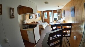 Una habitación pequeña y acogedora con paneles de madera, una kitchenette, una cama y un comedor.