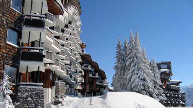 Una pista de esquí cubierta de nieve con un edificio de hotel de varios pisos a su lado.
