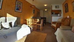 Una sala de estar acogedora con paredes de madera, un comedor con sillas de madera, un sofá y una mesa de centro.
