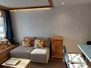 Una habitación acogedora con un conjunto de sofás, un pequeño armario de madera y una mesa.