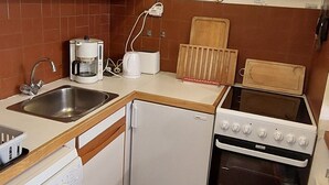 A compact kitchen with a sink, coffee maker, toaster, and a stove.