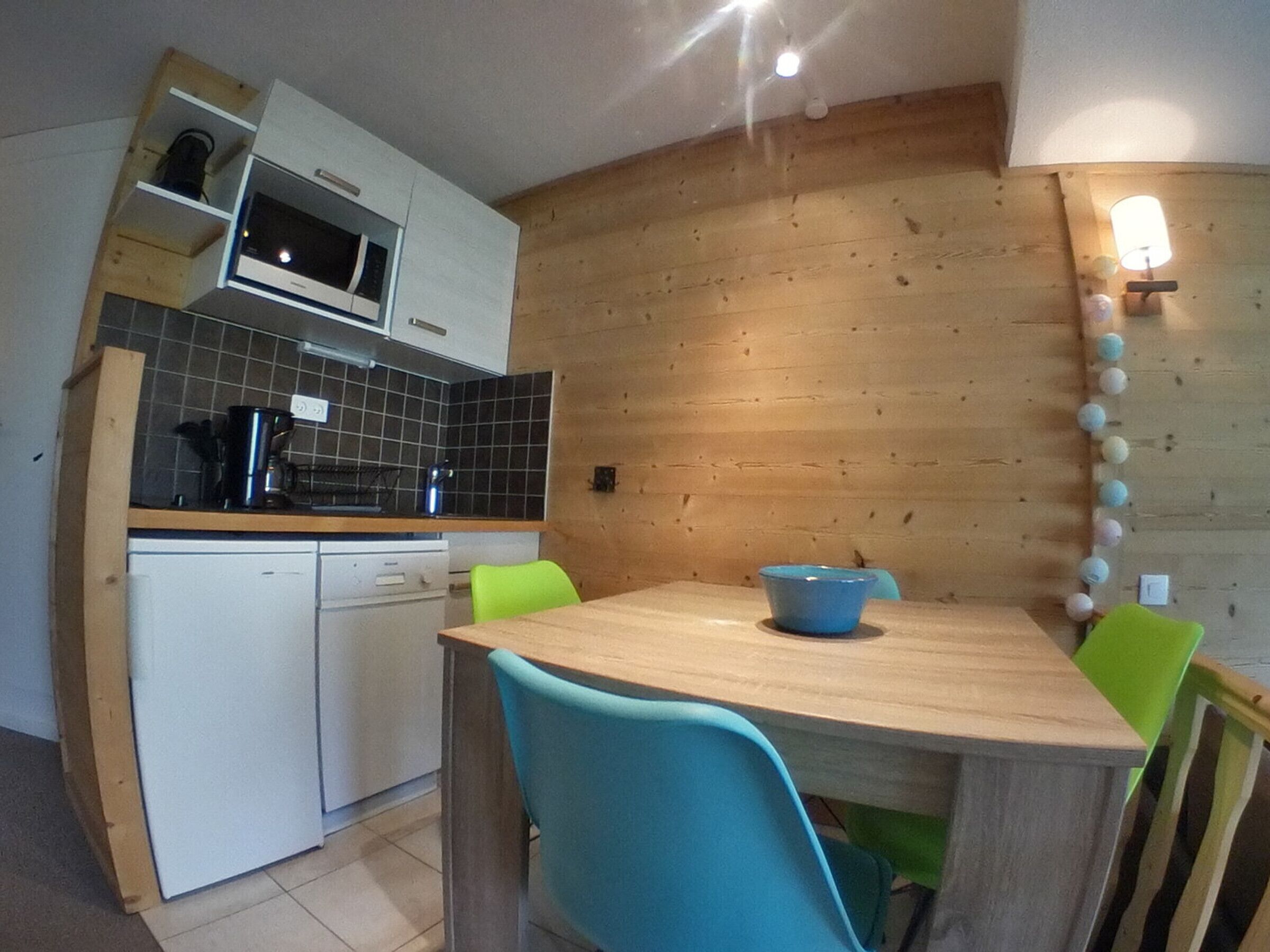 Una cocina compacta con microondas, lavamanos y comedor con mesa y sillas.