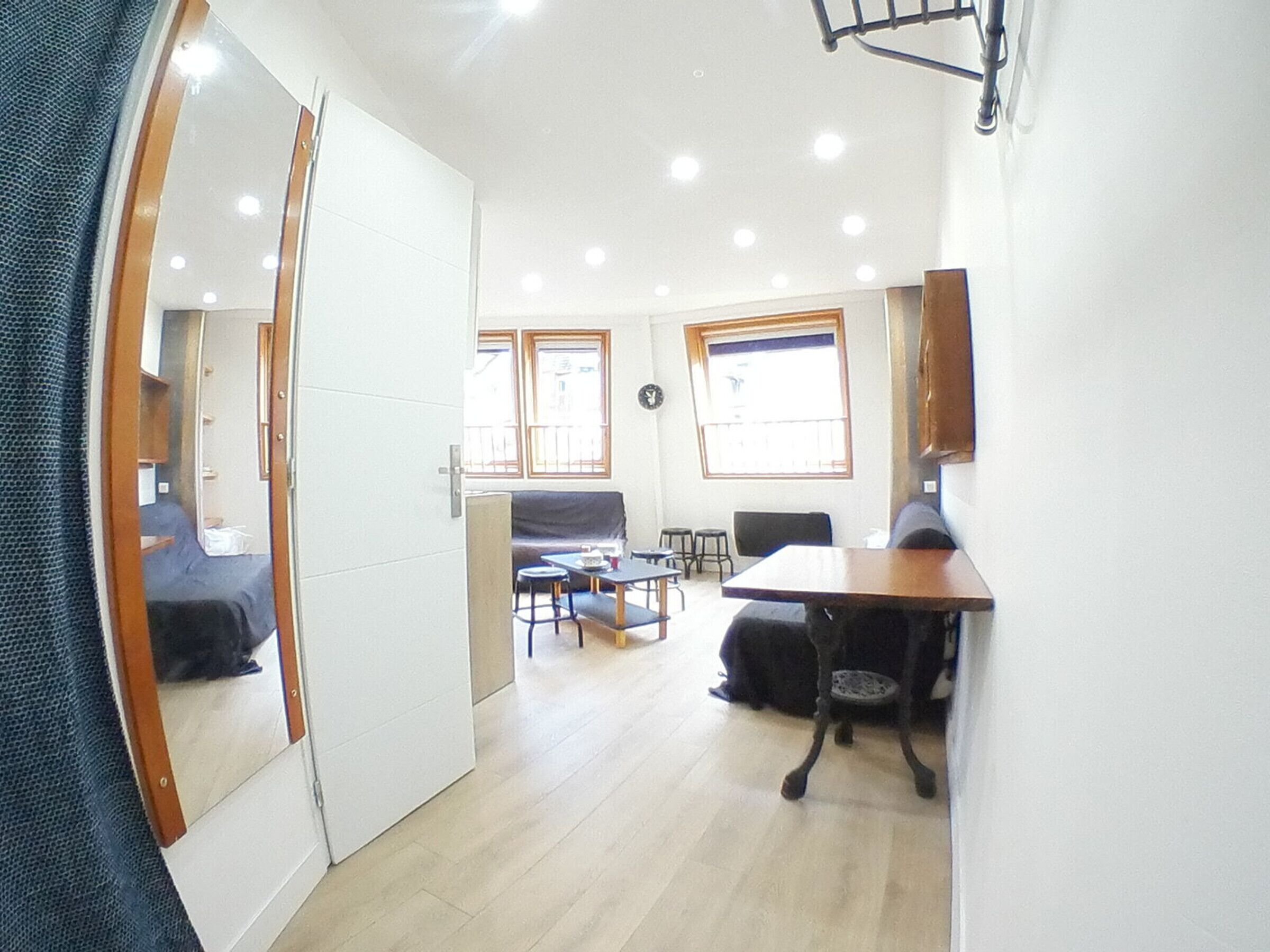 Un espace de vie compact comprenant un placard avec des portes miroir, une table à manger, un canapé et un petit coin cuisine.
