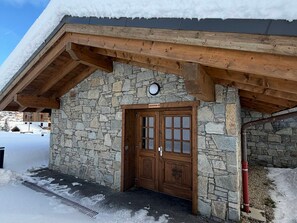 Ein Steinhaus mit einer Holztür und einem Schild darüber.