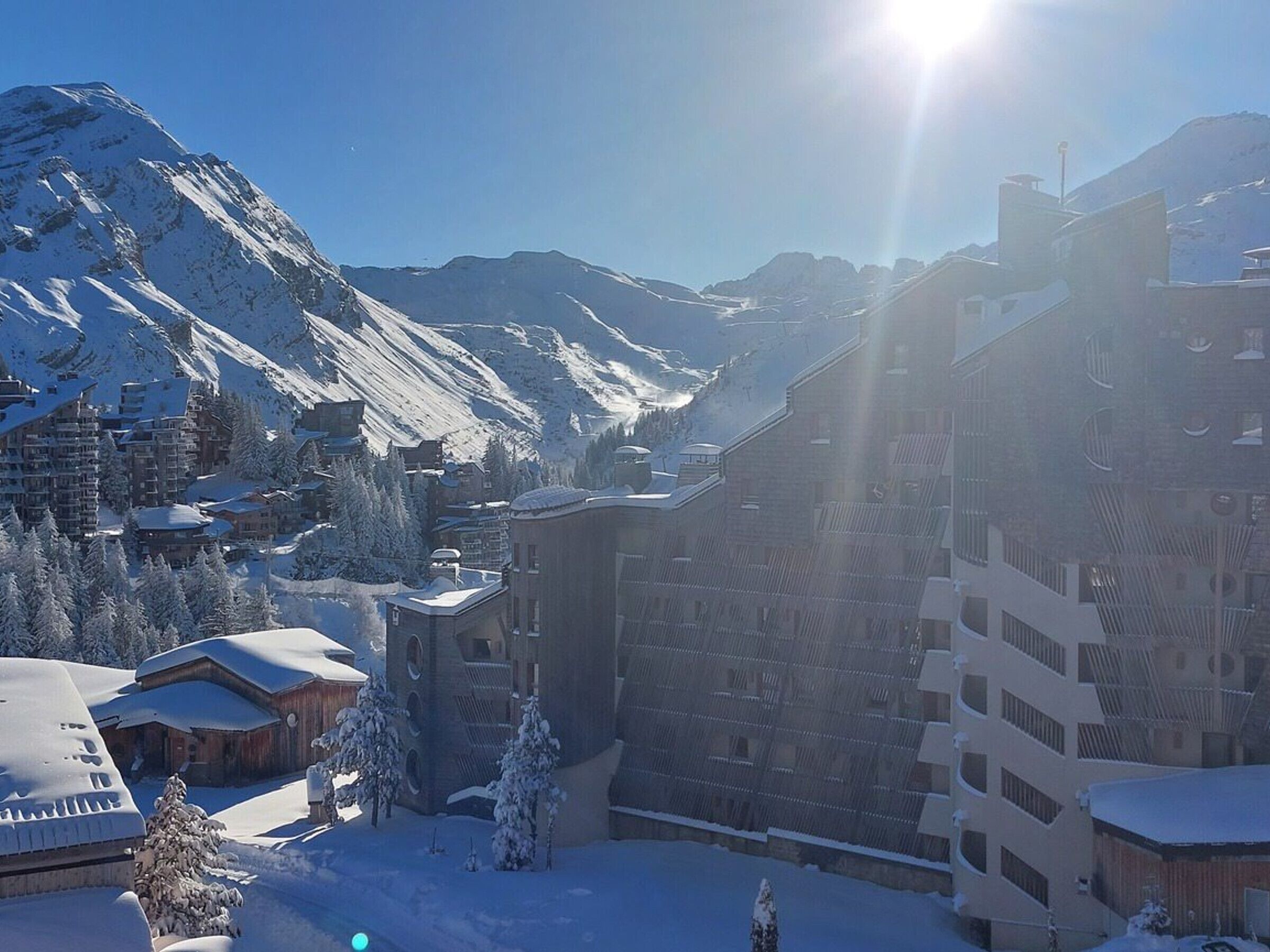 Un paese montano innevato con edifici, tra cui un grande albergo e una seggiovia ben visibile sullo sfondo.