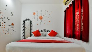 A neatly made bed with red pillows, a mirror, and red curtains. - Route 77 (Calangute)