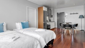 Una habitación de hotel moderna con dos camas, kitchenette, comedor y baño.