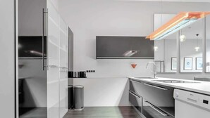 Una cocina moderna con horno empotrado, lavavajillas y un amplio ventanal sobre el fregadero.