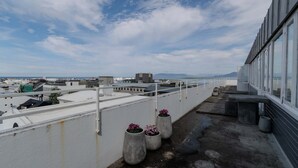 A rooftop terrace with concrete planters and a view of the cityscape and ocean.