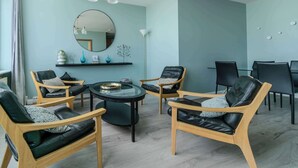 A modern living room with a round table, leather chairs, a large mirror, and a ceiling light fixture. - Mani Apartments -Studio with Balcony Downtown (Reykjavík)