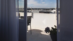 A balcony with a view of a cityscape, a chair, and a potted plant.
