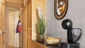 Un couloir en bois, orné d’une plante en pot, d’un saladier rempli de fruits et d’une machine à café posée sur un comptoir.