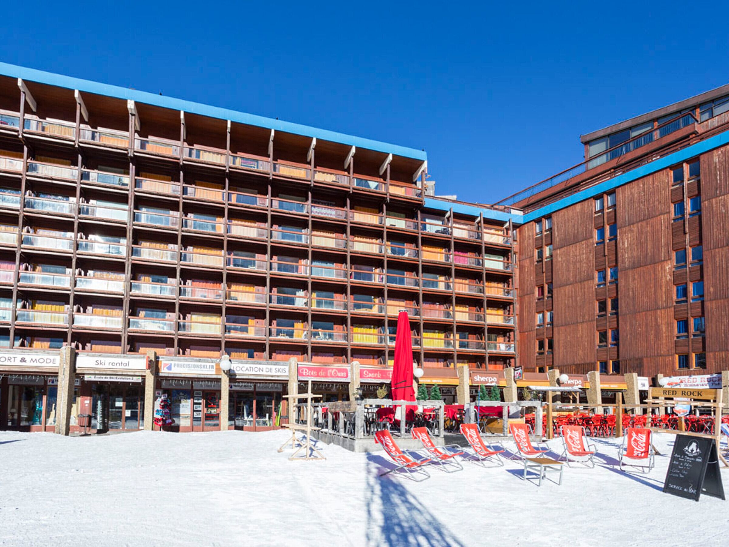 A multi-story hotel with balconies, outdoor seating, and various shops.