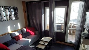 A compact living space with a sofa, a small table, and a window with curtains. - Modern apartment for 5 in the heart of Avoriaz (Avoriaz)