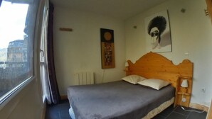 A bedroom with a bed, a window, a radiator, and a wall-mounted picture. - Modern apartment for 5 in the heart of Avoriaz (Avoriaz)