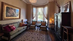 A traditional room with a sofa, armchairs, a chandelier, and a large painting.