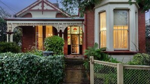 A Victorian-style house with a decorative facade, a front porch, and a small garden area.