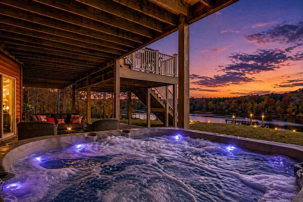 A hot tub with a view of a lake and autumn trees at sunset.