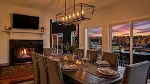 Un comedor con chimenea, un ventanal con vistas panorámicas y una lámpara moderna.