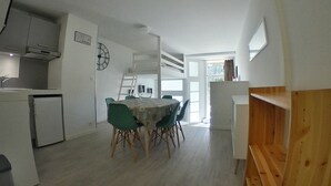 Une cuisine compacte avec un coin repas, un petit réfrigérateur et une horloge au mur.