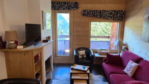 Ein gemütliches Wohnzimmer mit Holzvertäfelung, einem Fernseher, einem roten Sofa und einem Kamin.