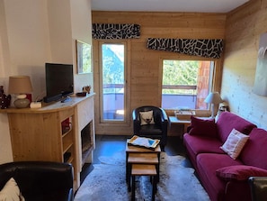 Un salon chaleureux avec un décor en bois, une télévision, un canapé rouge et une cheminée.