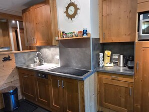 A kitchen with wooden cabinets, a stainless steel sink, and a clock on the wall.