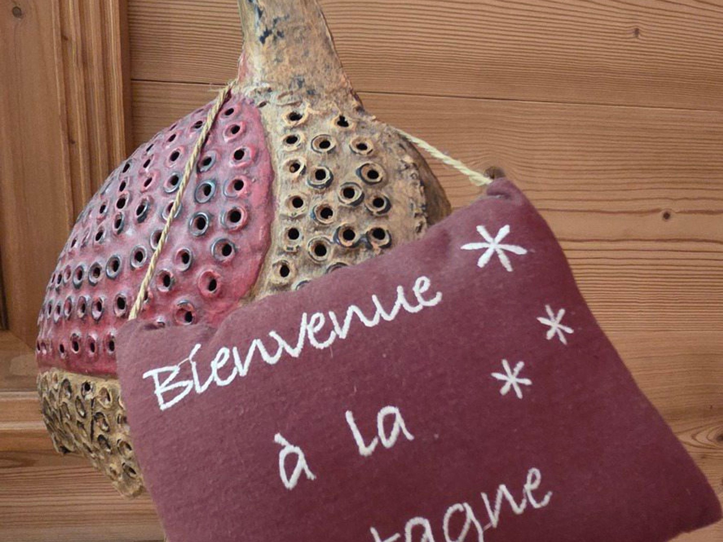 A wooden wall with a decorative item resembling a fish head and a pillow with the text 'Bienvenue à la montagne'.
