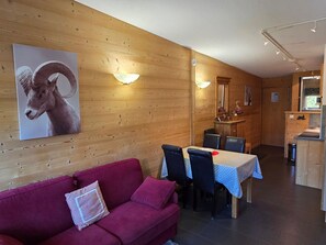 A wooden interior with a dining area, a sofa, and a wall-mounted lamp.