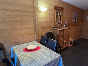A wooden interior with a dining table, chairs, a mirror, and a cabinet.
