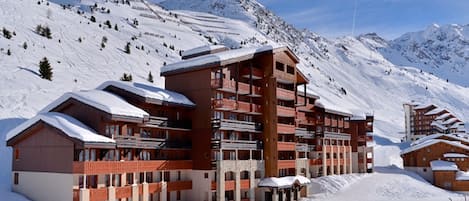 Un hotel a più piani con balconi, con vista su una montagna innevata.