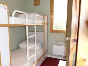 A bunk bed room with a window, a radiator, and a door.
