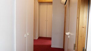Un pasillo con paredes blancas, alfombra roja y puertas de madera.