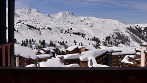 Paisaje montañoso nevado con edificios cubiertos de nieve, probablemente un complejo de esquí.