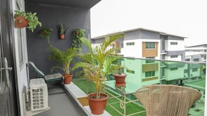 A balcony with potted plants, a wicker chair, and a small table. - Cozy bohemian loft in the heart of Lekki. Close to the beach, art gallery & mall (Lekki)