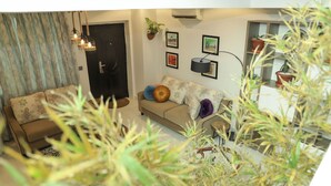 A living room with a sofa, a coffee table, and a potted plant. - Cozy bohemian loft in the heart of Lekki. Close to the beach, art gallery & mall (Lekki)